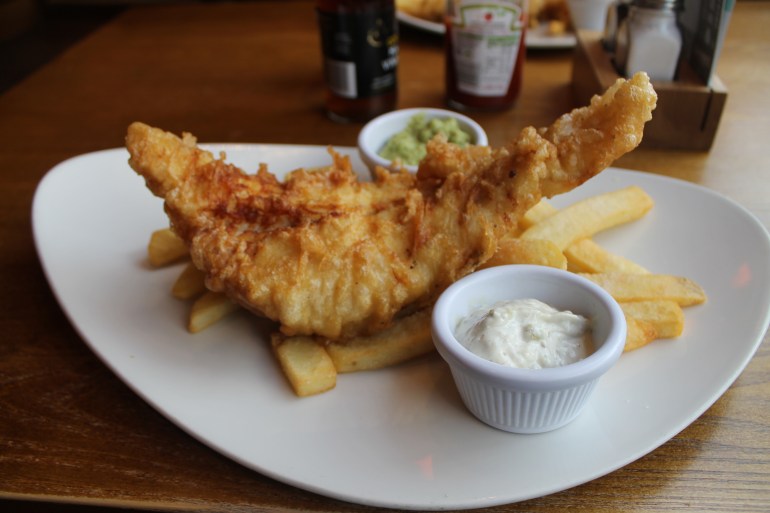 Tasty fish and chips served with tartar sauce and mushy peas.